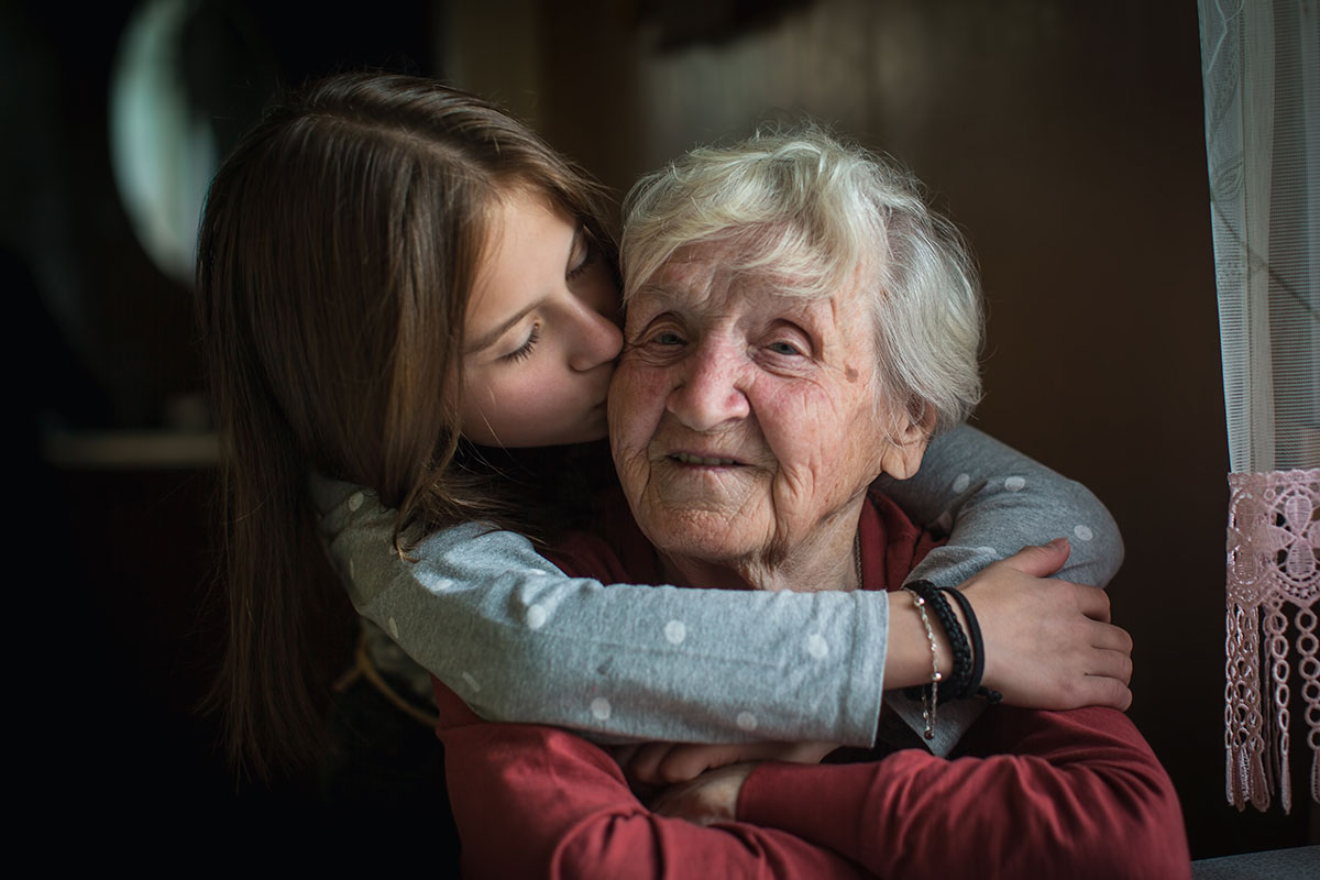 A child embracing an elderly woman