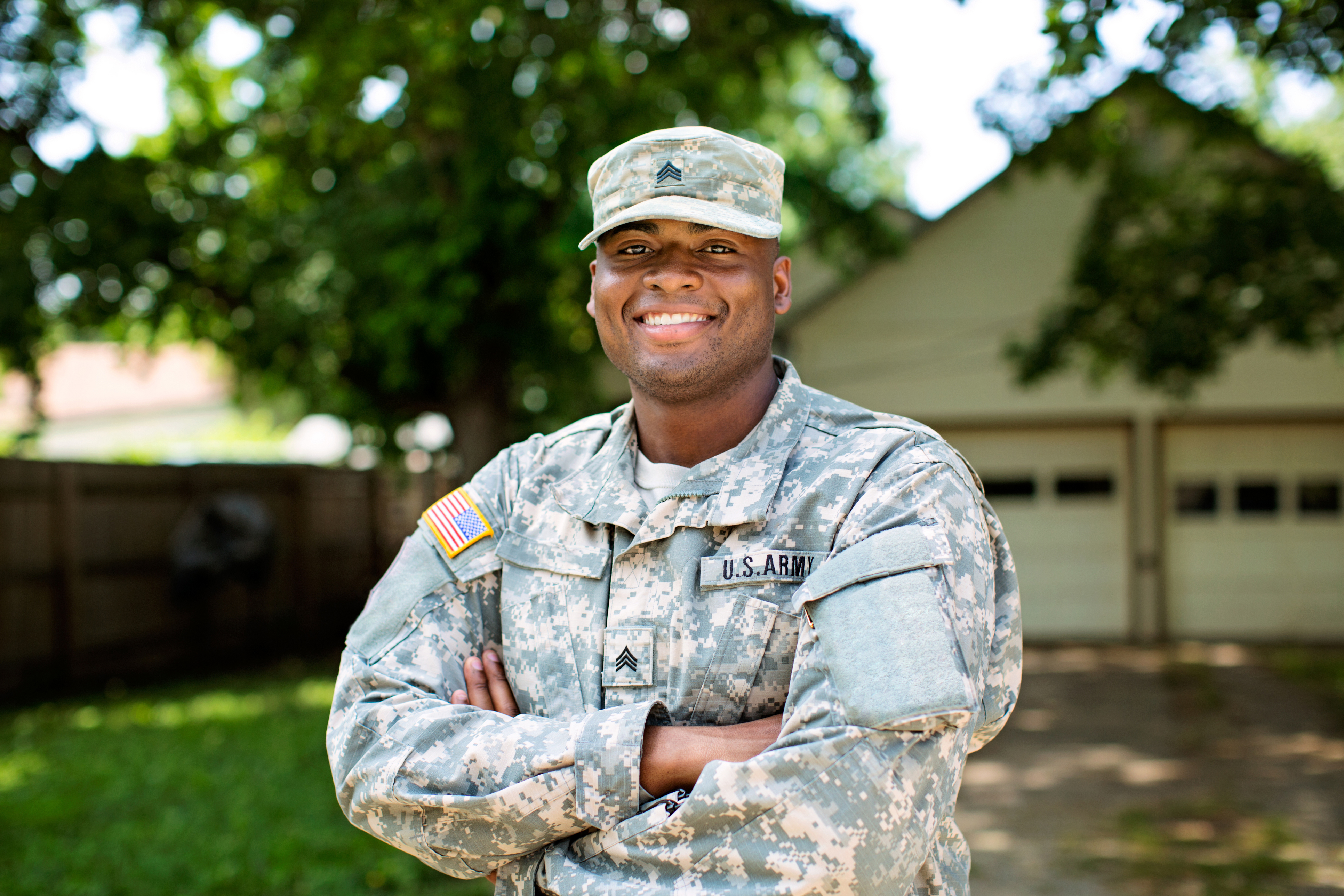 Member of U.S. Armed Forces standing in front of a house. 