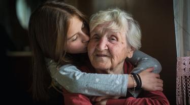 A child embracing an elderly woman