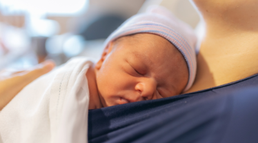 Newborn baby sleeping on mother's chest in hospital.